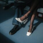 Close-up of fashionable black shoes and white high heels with pantyhose indoors.